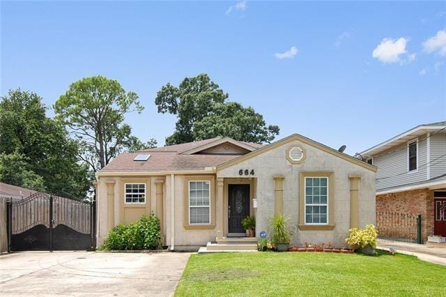 bungalow featuring fence, driveway, and a front yard