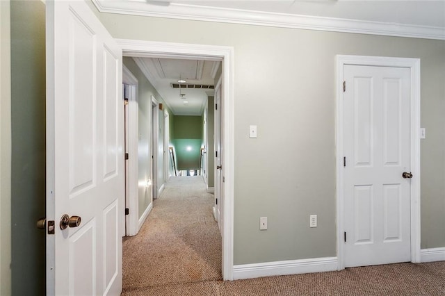 hall featuring carpet floors, crown molding, baseboards, and attic access