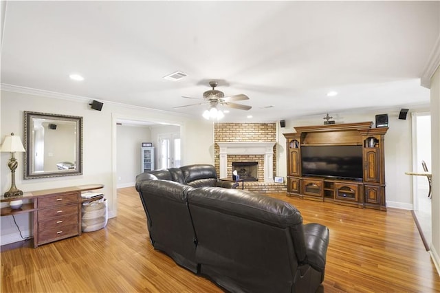 living room with crown molding, visible vents, a ceiling fan, and wood finished floors