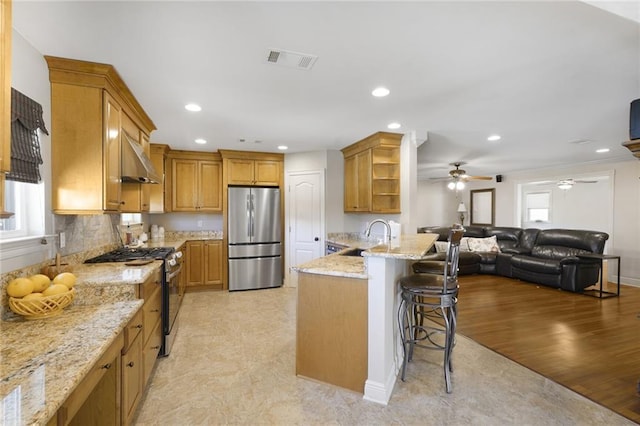 kitchen featuring open shelves, a kitchen bar, a peninsula, appliances with stainless steel finishes, and visible vents