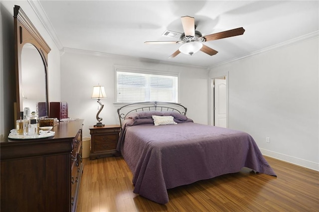bedroom featuring crown molding, baseboards, ceiling fan, and wood finished floors
