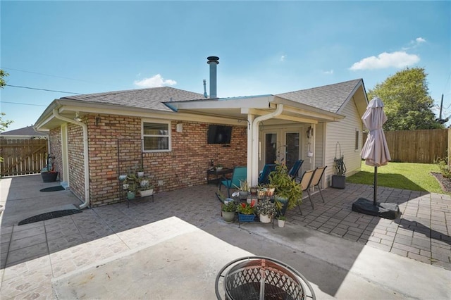 rear view of house with brick siding, fence, a shingled roof, and a patio area