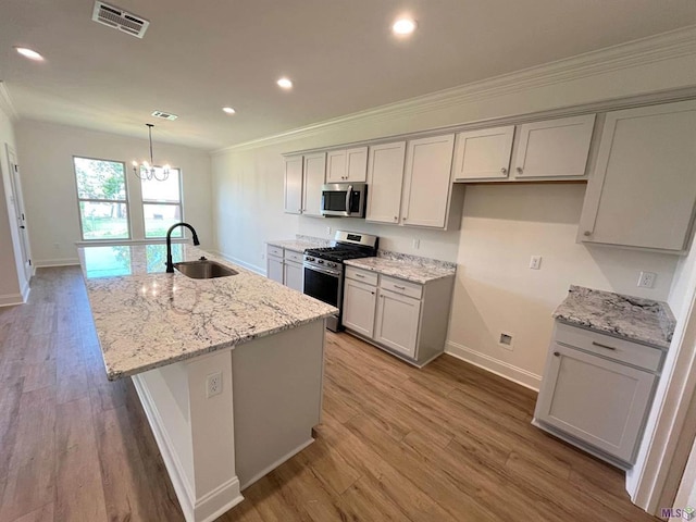 129 Olivia Dr, Luling, LA 70070 - kitchen with appliances with stainless steel finishes, crown molding, a kitchen island with sink, wood finished floors, and a chandelier