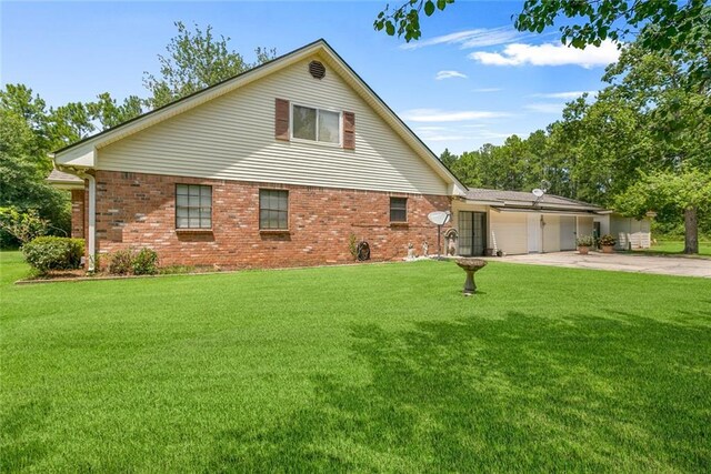 65398 Maple St, Mandeville, LA 70448 - view of front of house featuring a garage, driveway, a front yard, and brick siding