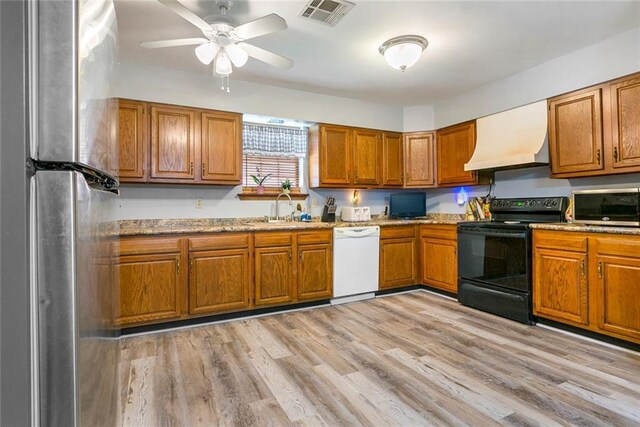 65398 Maple St, Mandeville, LA 70448 - kitchen with stainless steel appliances, a sink, brown cabinetry, custom exhaust hood, and light wood-type flooring