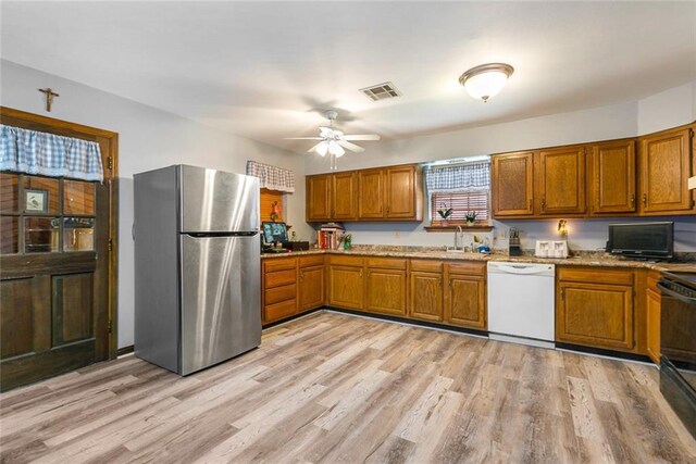 65398 Maple St, Mandeville, LA 70448 - kitchen with white dishwasher, freestanding refrigerator, and brown cabinets