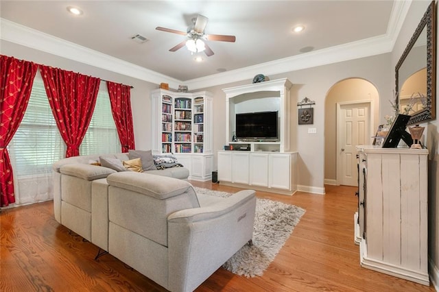 living area with a ceiling fan, light wood-style flooring, visible vents, crown molding, and arched walkways