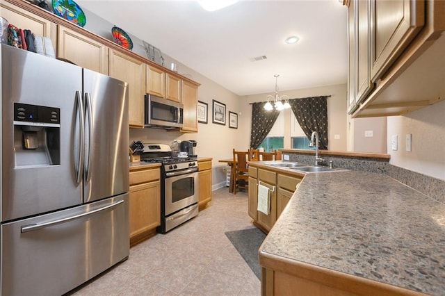 kitchen with a sink, a peninsula, an inviting chandelier, light tile patterned floors, and appliances with stainless steel finishes
