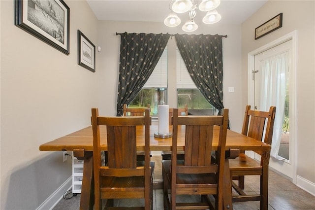 dining space with baseboards, a notable chandelier, and tile patterned floors