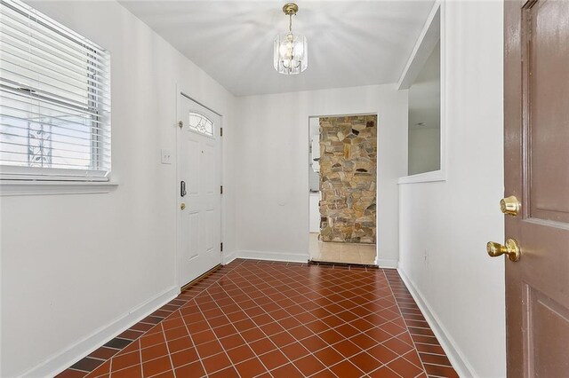 3013 Volpe Dr, Chalmette, LA 70043 - foyer entrance with an inviting chandelier, baseboards, and dark tile patterned flooring