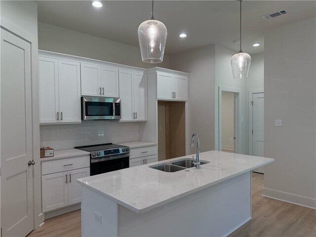 75396 Henderson Rd, Covington, LA 70435 - kitchen with stainless steel appliances, light wood-style floors, tasteful backsplash, white cabinets, and light stone counters