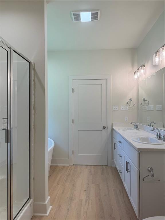 75396 Henderson Rd, Covington, LA 70435 - bathroom with wood finished floors, a stall shower, double vanity, and a freestanding tub