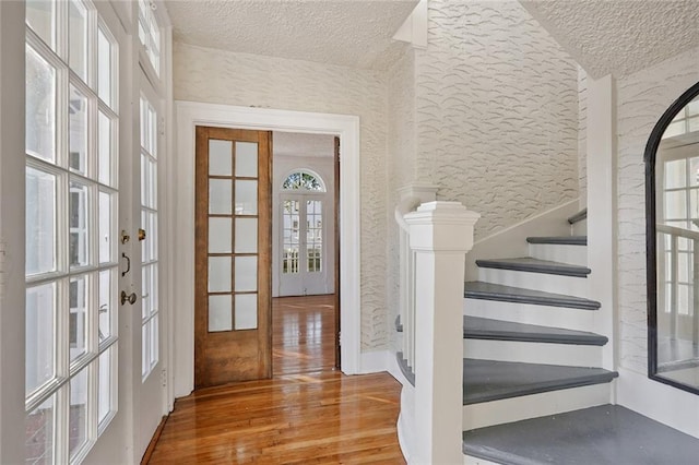 4237 Fontainebleau Dr, New Orleans, LA 70125 - entryway featuring french doors, a textured ceiling, wood finished floors, and stairs