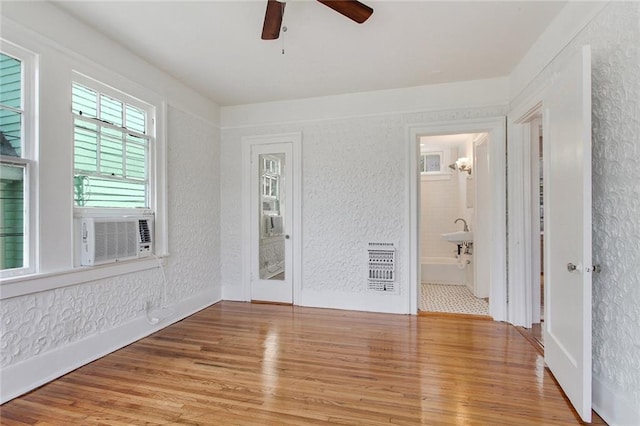 4237 Fontainebleau Dr, New Orleans, LA 70125 - unfurnished room with heating unit, wood finished floors, a ceiling fan, cooling unit, and a textured wall