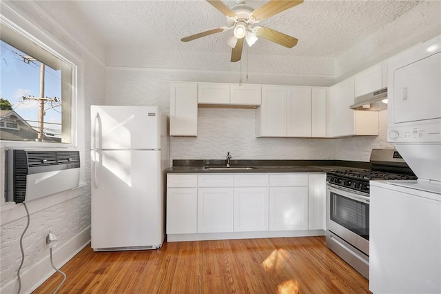 4237 Fontainebleau Dr, New Orleans, LA 70125 - kitchen with freestanding refrigerator, under cabinet range hood, a textured ceiling, stainless steel gas stove, and white cabinets