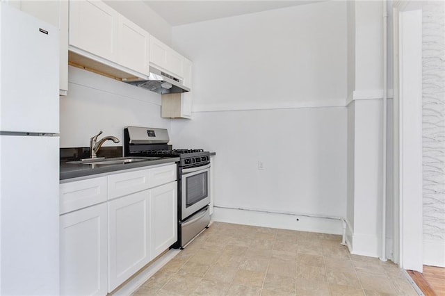 4237 Fontainebleau Dr, New Orleans, LA 70125 - kitchen with freestanding refrigerator, stainless steel range with gas cooktop, under cabinet range hood, dark countertops, and white cabinets