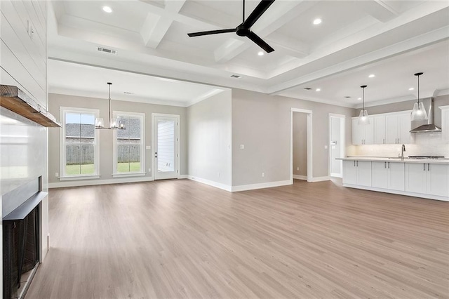 unfurnished living room featuring baseboards, beamed ceiling, a fireplace, and light wood-type flooring