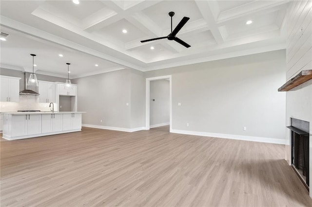 unfurnished living room featuring a multi sided fireplace, a sink, beamed ceiling, and light wood finished floors