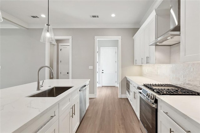 kitchen featuring white cabinetry, a sink, visible vents, appliances with stainless steel finishes, and wall chimney exhaust hood