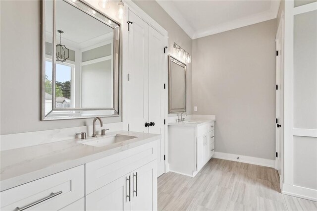 full bathroom featuring baseboards, crown molding, a sink, and two vanities