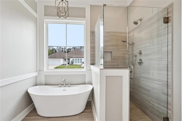 bathroom with baseboards, a notable chandelier, a soaking tub, and a shower stall
