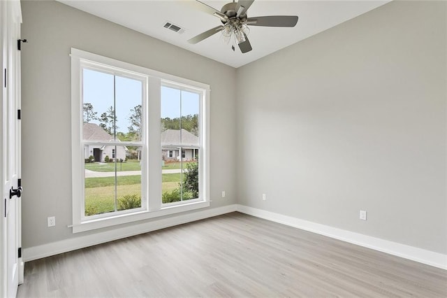 unfurnished room featuring baseboards, visible vents, a ceiling fan, and wood finished floors