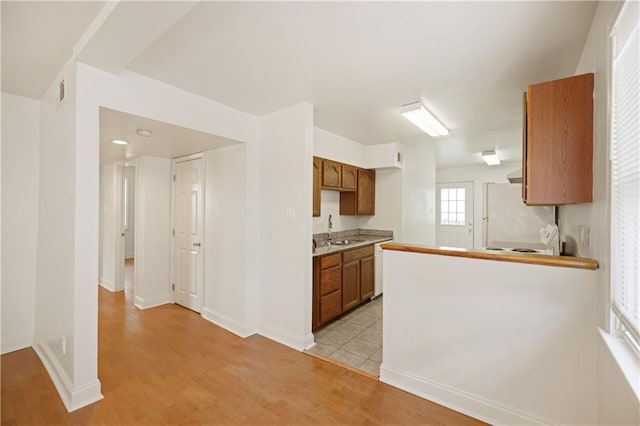 kitchen with a sink, light countertops, freestanding refrigerator, and light wood-type flooring
