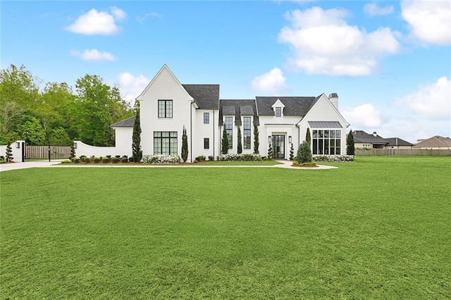 view of front of house featuring stucco siding, a chimney, fence, and a front yard