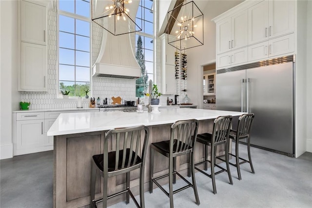 kitchen featuring stainless steel built in fridge, finished concrete flooring, tasteful backsplash, and a chandelier