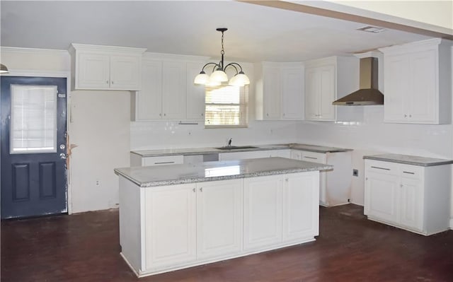 41158 2nd Colonial St, Prairieville, LA 70769 - kitchen featuring white cabinetry, a center island, a sink, a notable chandelier, and wall chimney exhaust hood