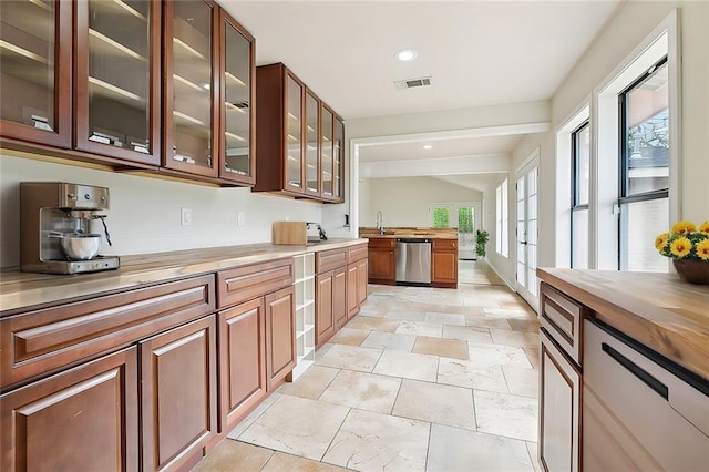 4741 Lafon Dr, New Orleans, LA 70126 - kitchen featuring vaulted ceiling, dishwasher, wooden counters, glass insert cabinets, and visible vents