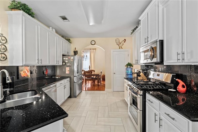 301 Clover Meadows Dr, Covington, LA 70433 - kitchen featuring stainless steel appliances, a sink, arched walkways, and white cabinets