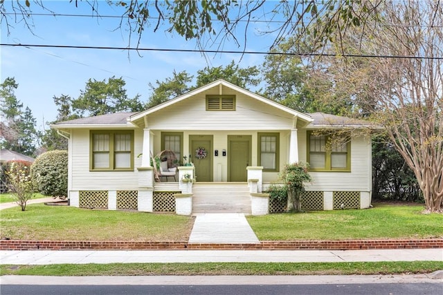 bungalow-style home with driveway, a shingled roof, a front lawn, and covered porch