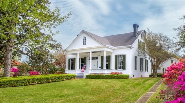 view of front facade with a front lawn, a chimney, and covered porch