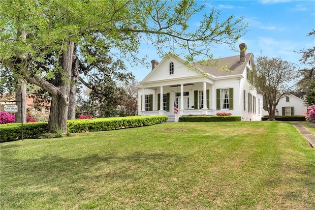 back of house featuring a chimney, a porch, and a yard