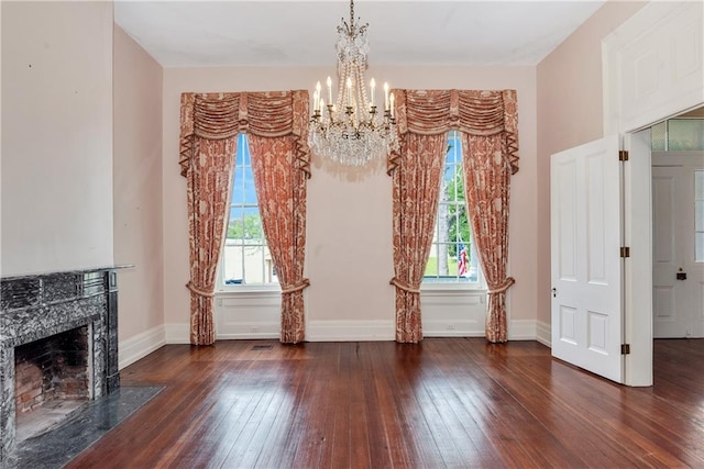 unfurnished living room featuring hardwood / wood-style floors, a wealth of natural light, and an inviting chandelier