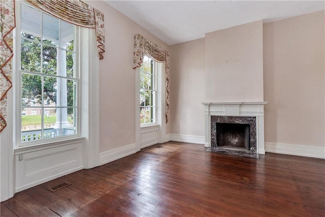 unfurnished living room with baseboards, hardwood / wood-style floors, visible vents, and a premium fireplace