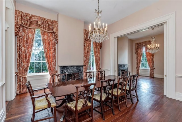 dining area featuring dark wood-style flooring, a notable chandelier, and a fireplace