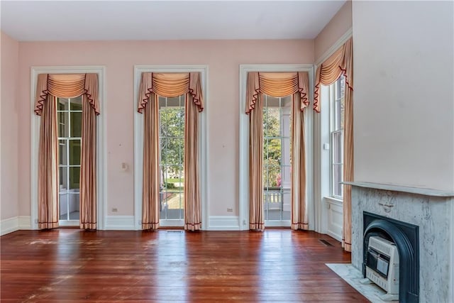 unfurnished living room featuring hardwood / wood-style floors, visible vents, baseboards, and heating unit