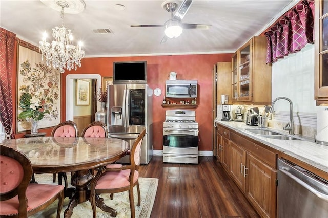 1830 Burgundy St, New Orleans, LA 70116 - kitchen with appliances with stainless steel finishes, a chandelier, brown cabinetry, dark wood-style floors, and glass insert cabinets