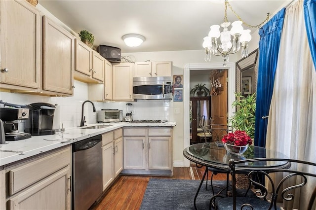 1830 Burgundy St, New Orleans, LA 70116 - kitchen featuring stainless steel appliances, a chandelier, decorative backsplash, dark wood-type flooring, and light stone counters