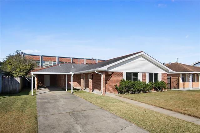 ranch-style home featuring fence, a front yard, brick siding, driveway, and a carport