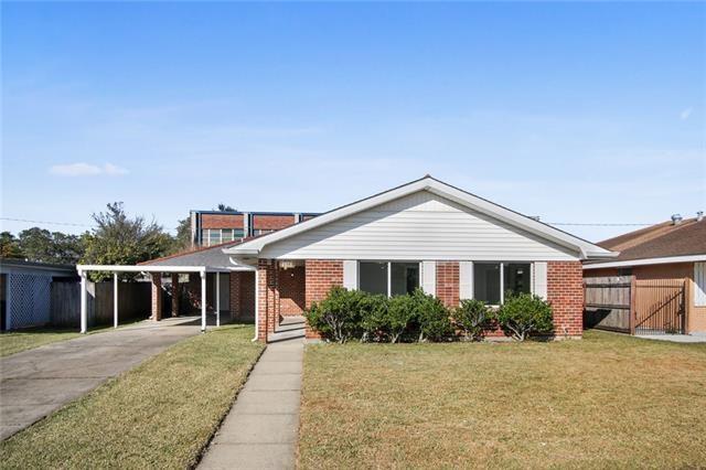 view of front of house featuring concrete driveway, fence, a front yard, brick siding, and a carport
