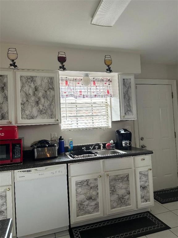 3417 Shangri La Dr, Chalmette, LA 70043 - kitchen featuring dark countertops, white dishwasher, a sink, and white cabinets