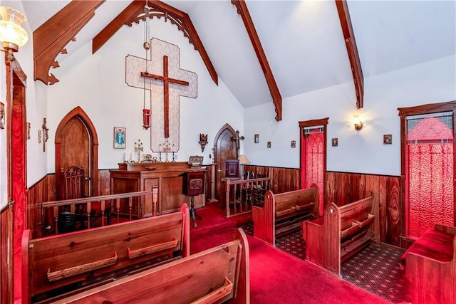 interior space with a wainscoted wall, carpet flooring, arched walkways, beam ceiling, and wood walls