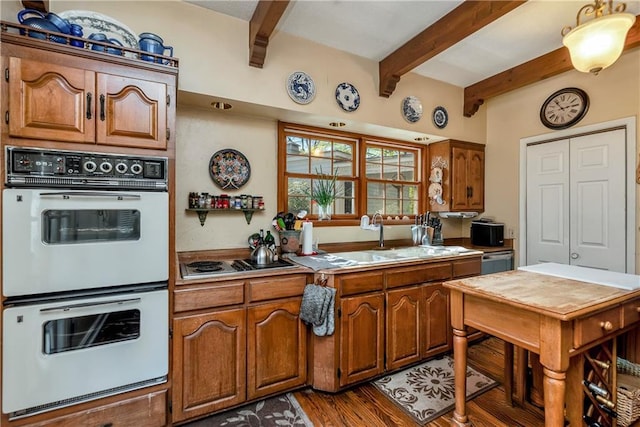 kitchen featuring brown cabinetry, electric stovetop, a sink, and double oven
