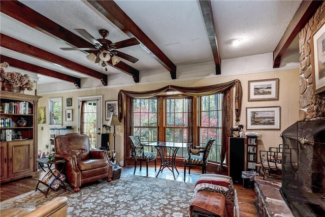 living area featuring a ceiling fan, wood finished floors, a textured ceiling, and plenty of natural light