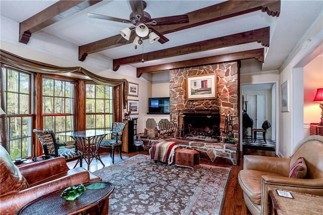 living area with a fireplace, wood finished floors, beamed ceiling, and ceiling fan