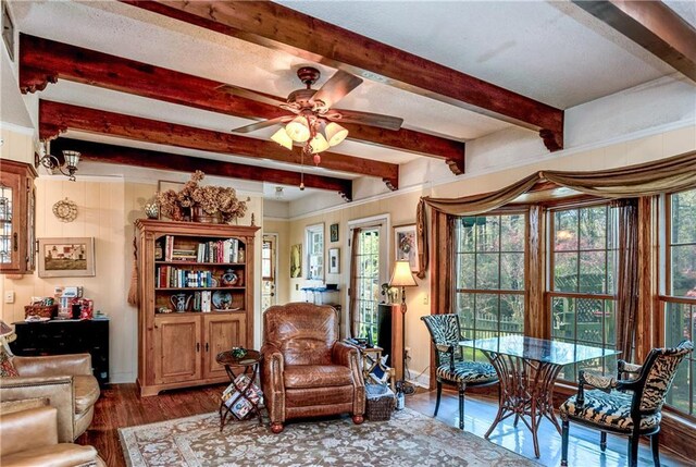 interior space with ceiling fan, baseboards, wood finished floors, and beam ceiling