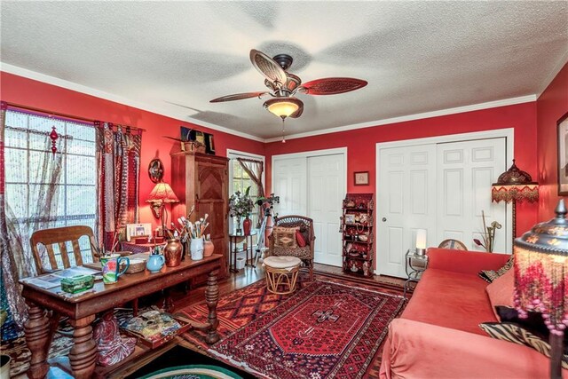 living area with a textured ceiling, a wealth of natural light, and ceiling fan